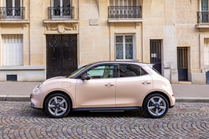 Der GWM ORA 03 in Galaxy Beige im Sommer geparkt mitten in einer romantischen Altstadt im Süden Europas, die beige Fassade des Hauses passt perfekt zum warmen Galaxy Beige des GWM ORA 03